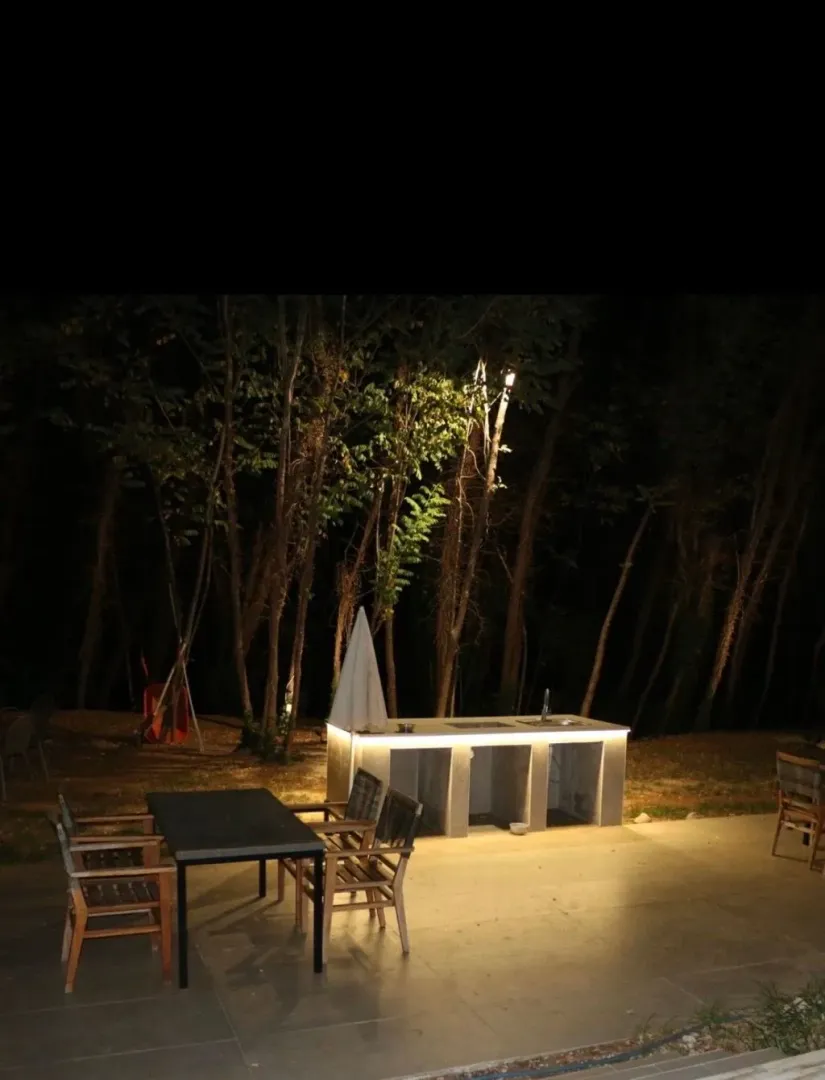 Illuminated outdoor kitchen and dining area in the yard.