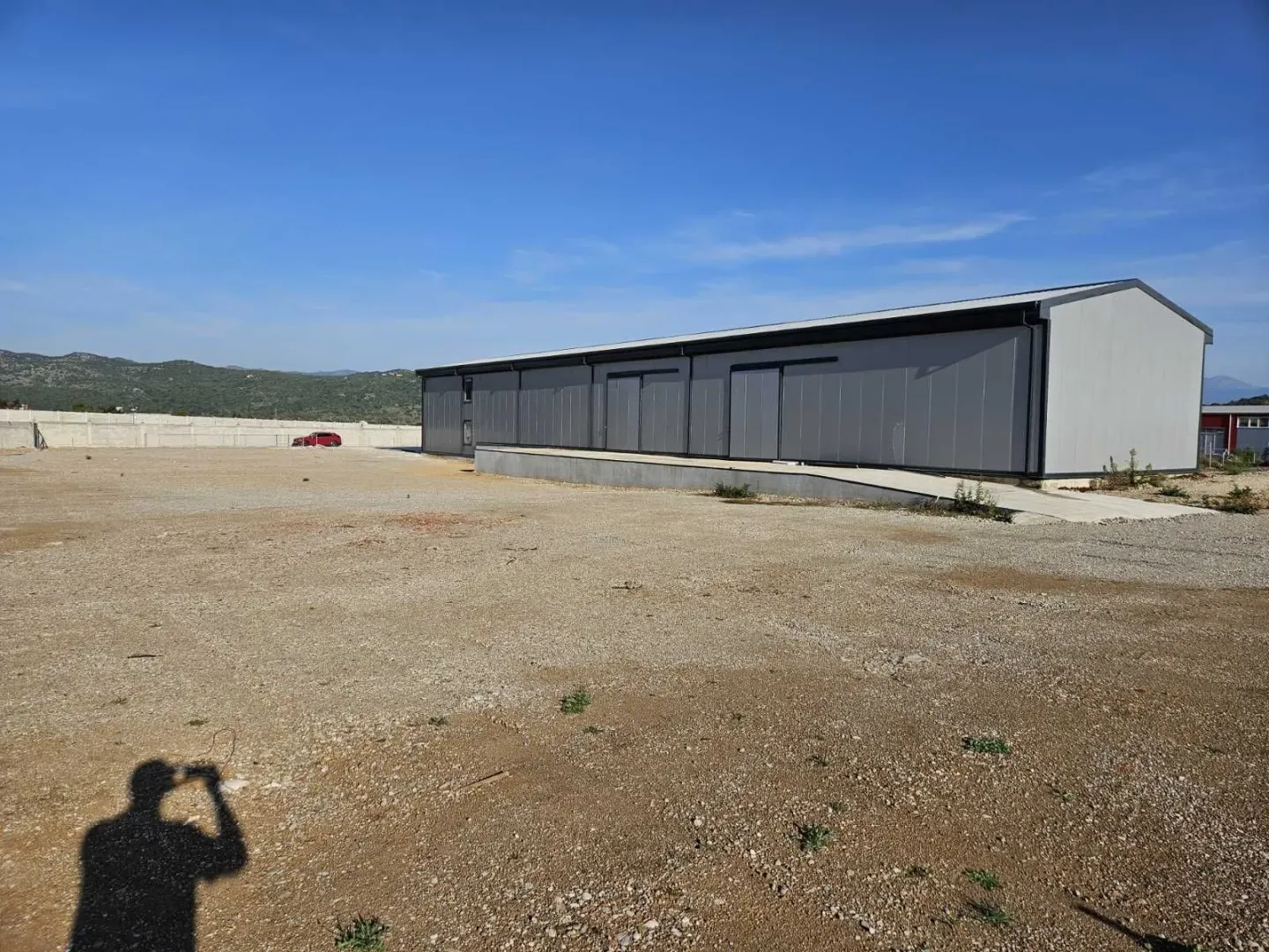 A modern industrial building with a spacious yard under a blue sky.