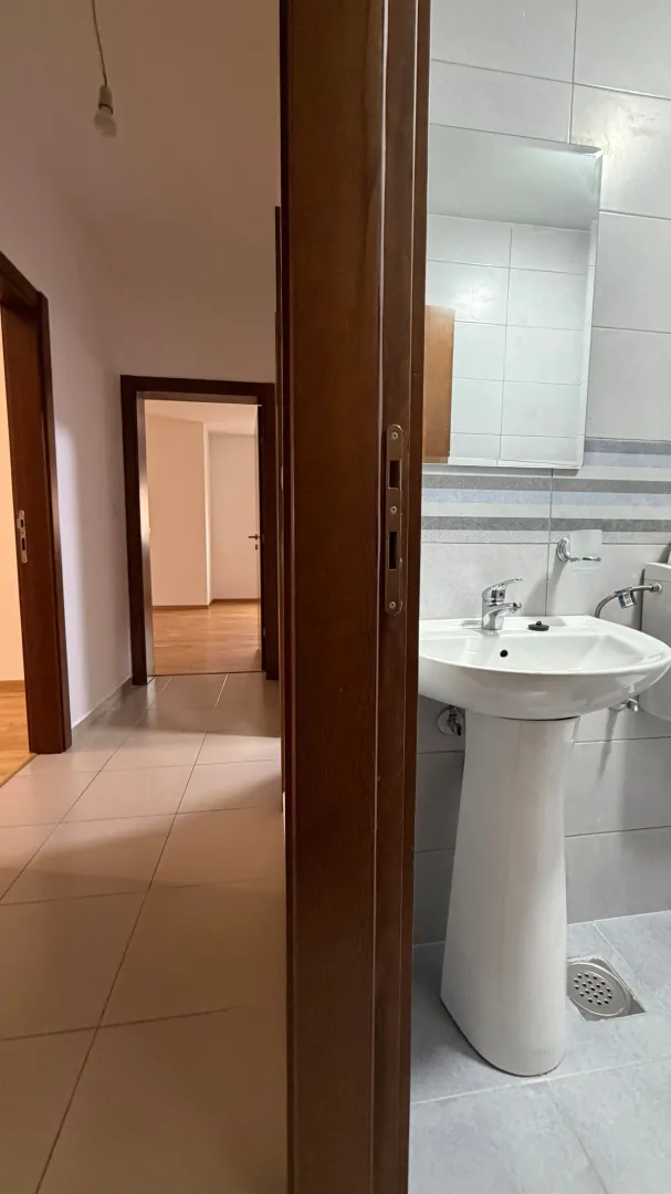 Pogled iz hodnika na kupatilo sa umivaonikom i ogledalom.