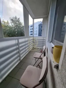 Zastakljeni balkon sa stolicama i pogledom na susedne zgrade. - image 15