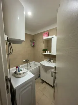 Small bathroom with a bathtub, washbasin, and washing machine. - image 11