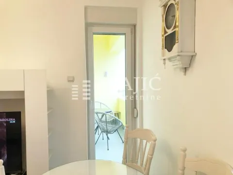 View from the living room towards the balcony with a dining table and a wall clock. - image 12