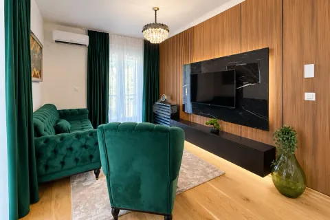 Modern living room with a green sofa set and a wooden wall panel with a television. - image 9