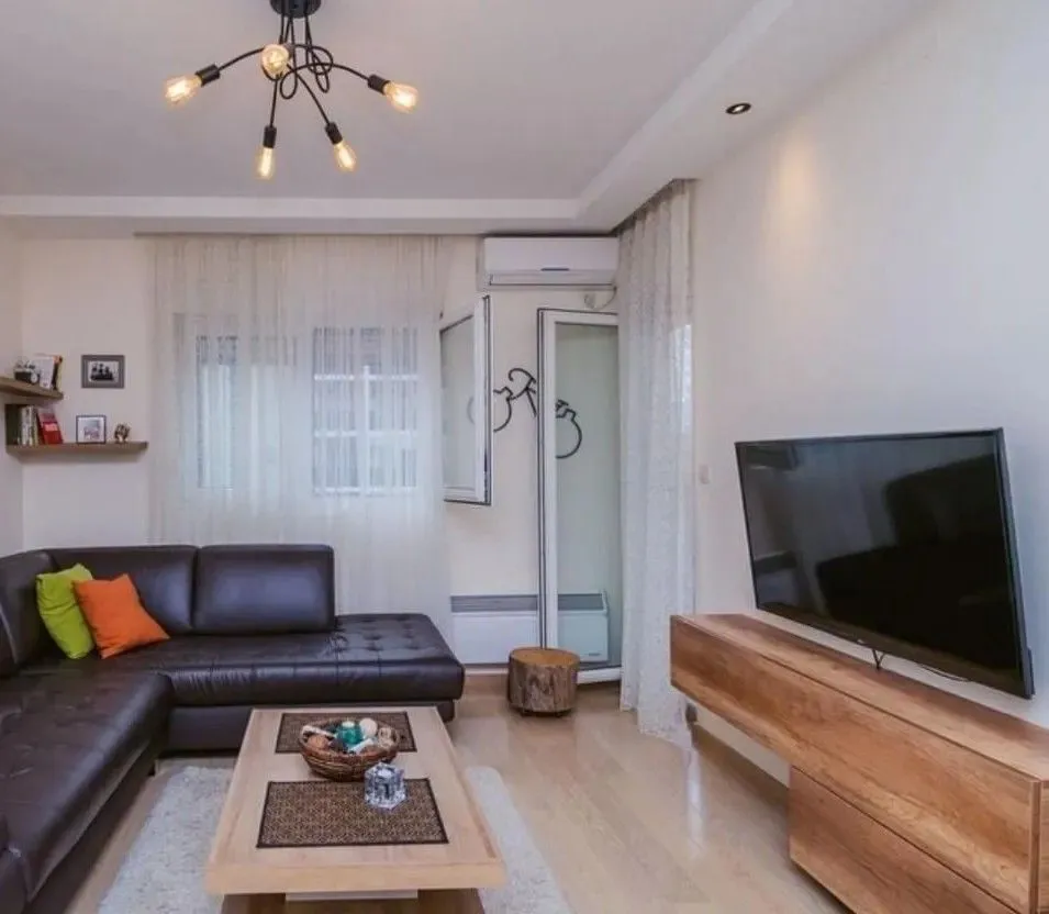 Living room with a dark sectional sofa, wooden coffee table, and television.