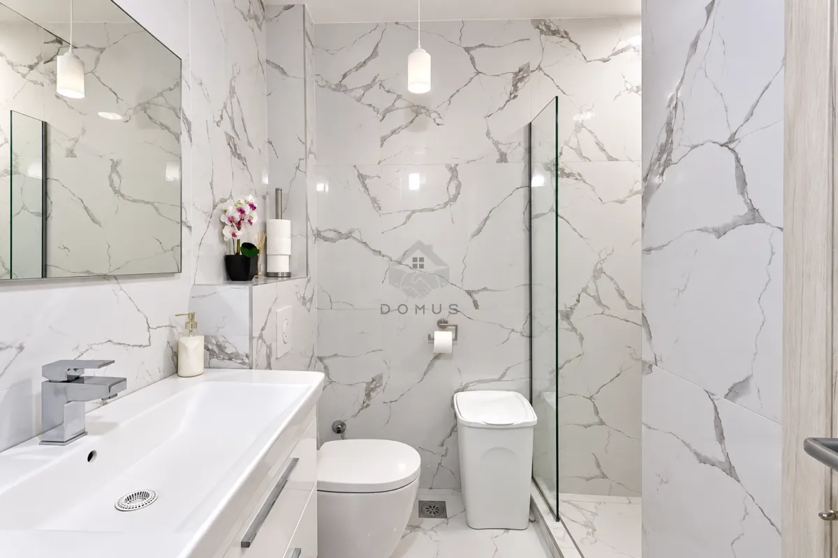 Modern bathroom tiled with marble-pattern ceramic tiles and a walk-in shower.