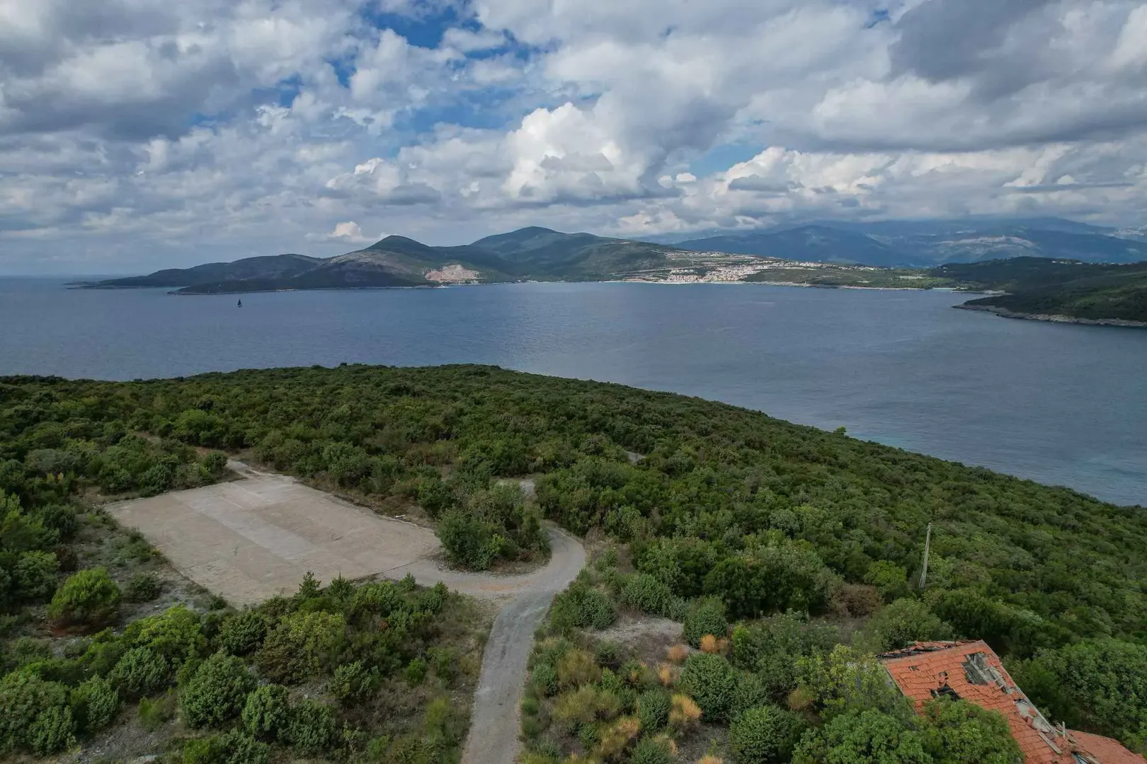 Pogled iz vazduha na more, obalu i brdoviti pejzaž.