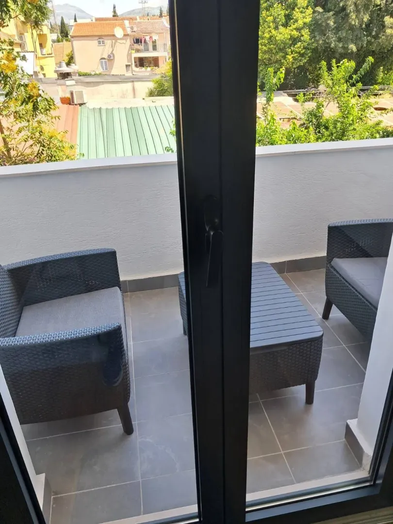 Small furnished balcony with seating furniture and a view of the surroundings.