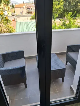 Small furnished balcony with seating furniture and a view of the surroundings. - image 4