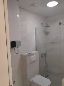 Bright bathroom featuring a walk-in shower, toilet, and water heater. - image 6