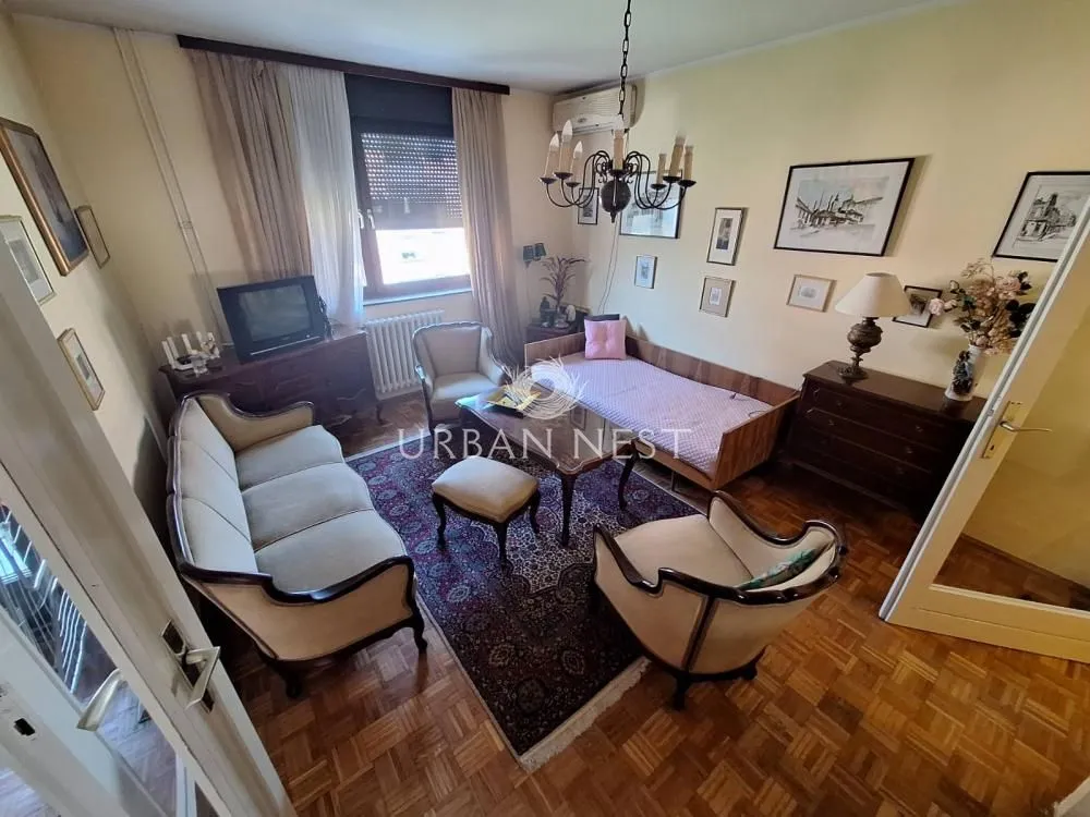 Furnished living room with seating set and parquet flooring.