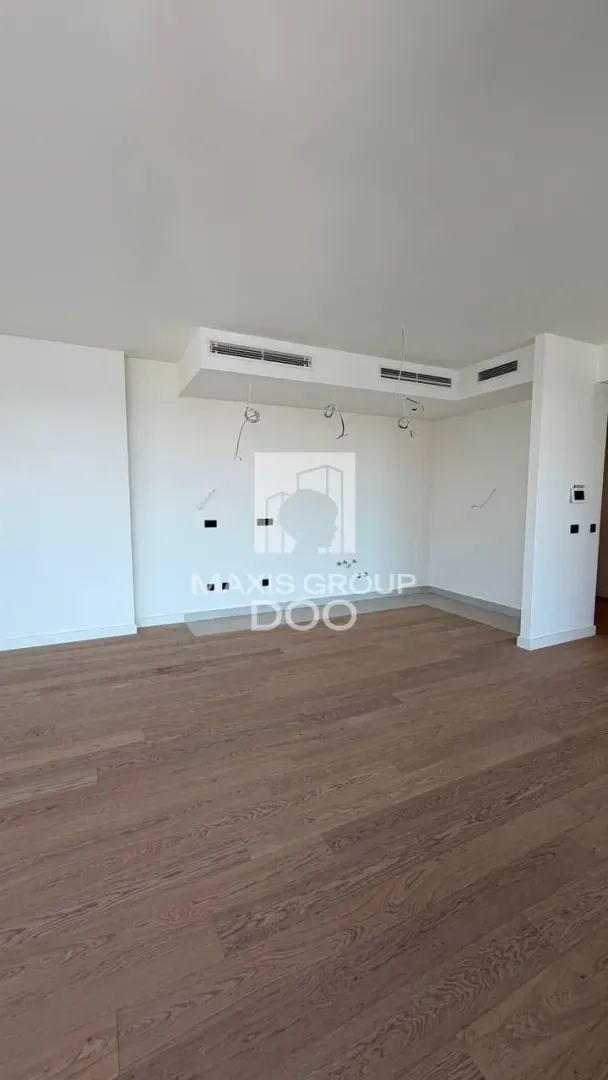 Prazna prostorija sa drvenim podom i spuštenim plafonom sa ventilacijom.