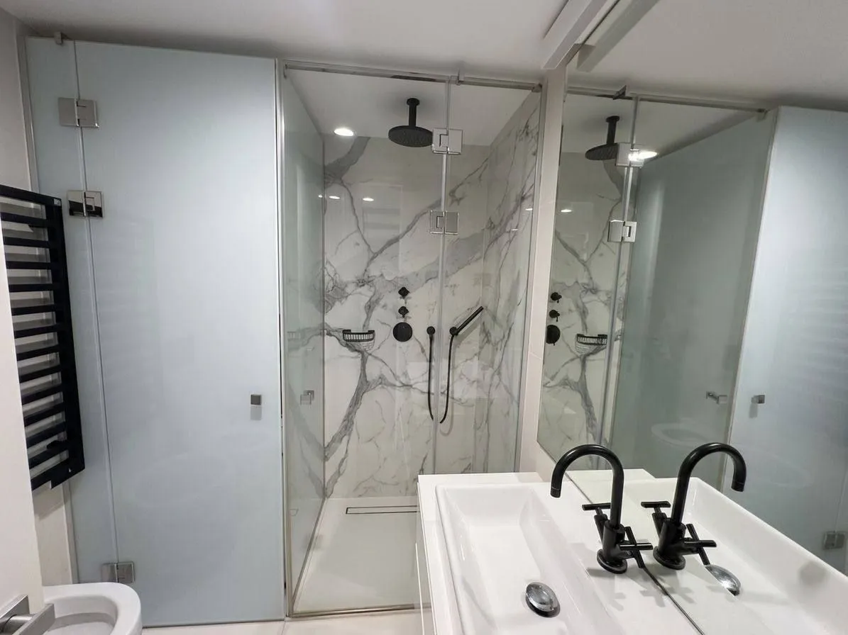 Modernly equipped bathroom with a walk-in shower and marble tiles.
