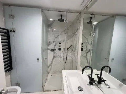 Modernly equipped bathroom with a walk-in shower and marble tiles. - image 9