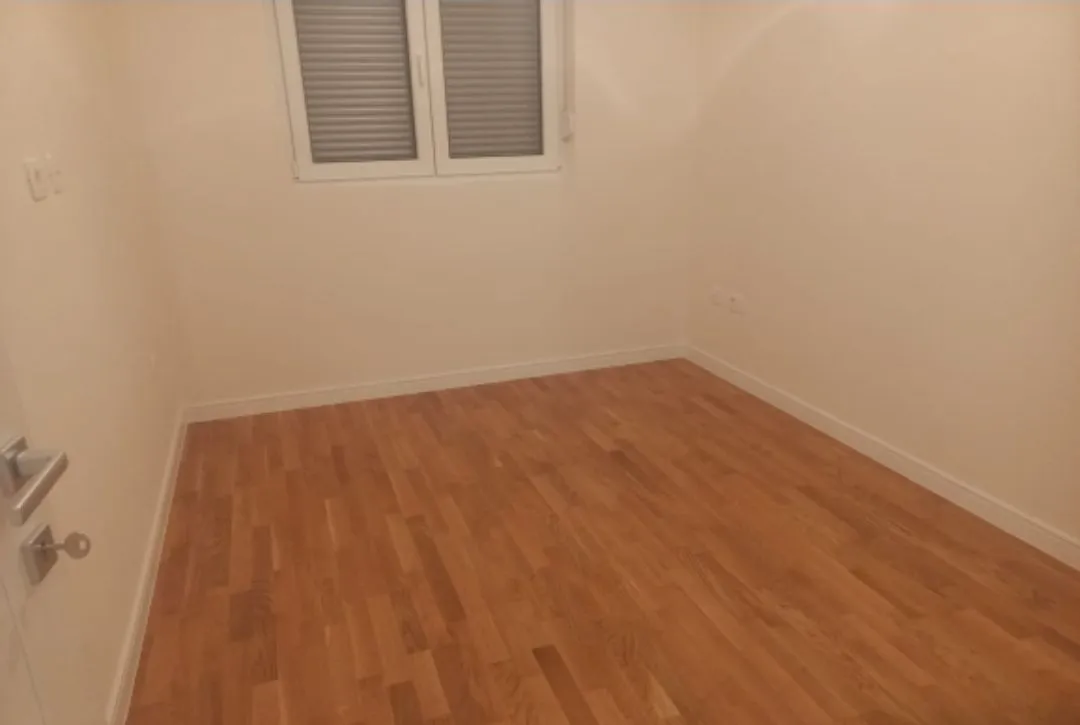 Empty room with light walls and wooden flooring.