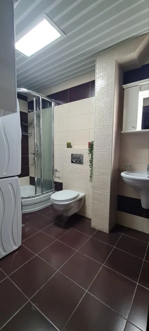 Moderno opremljeno kupatilo sa tuš kabinom i sanitarijama.