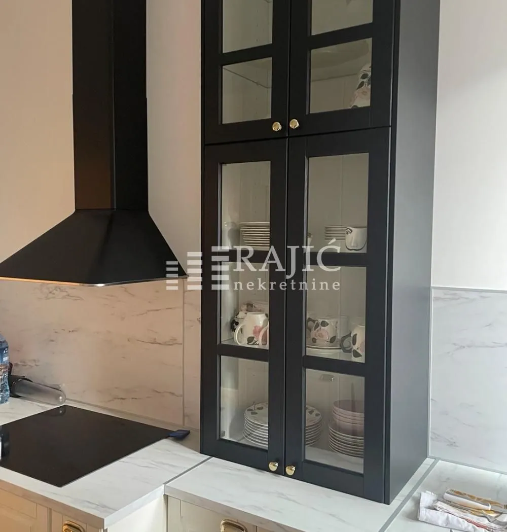Kitchen detail showing black wall cabinets and a range hood.