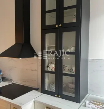 Kitchen detail showing black wall cabinets and a range hood. - image 10