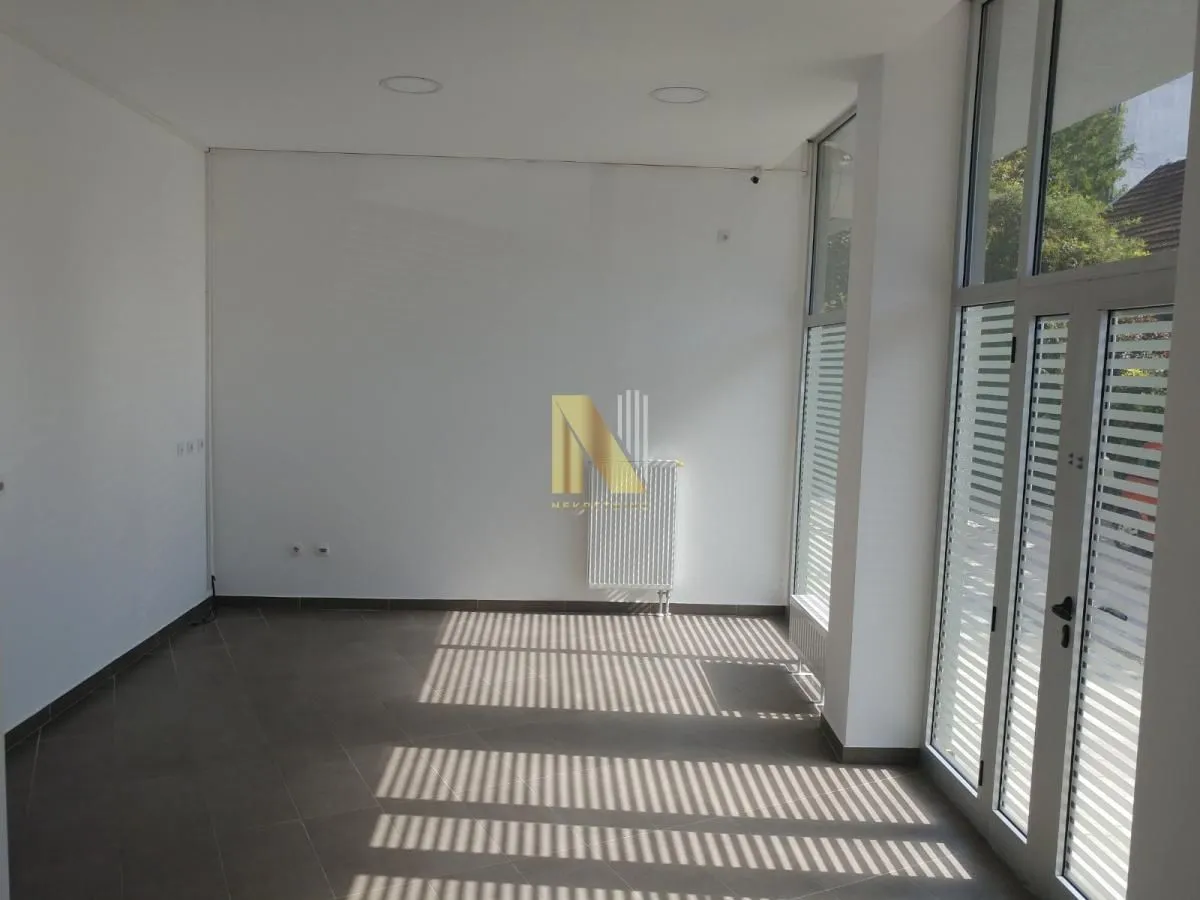 Empty bright room with large windows and tiled flooring.