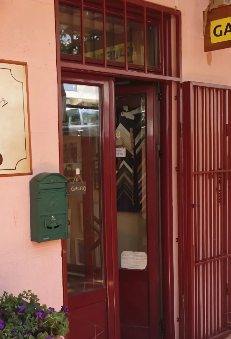 Entrance to a commercial space with dark red wooden doors and a green mailbox.