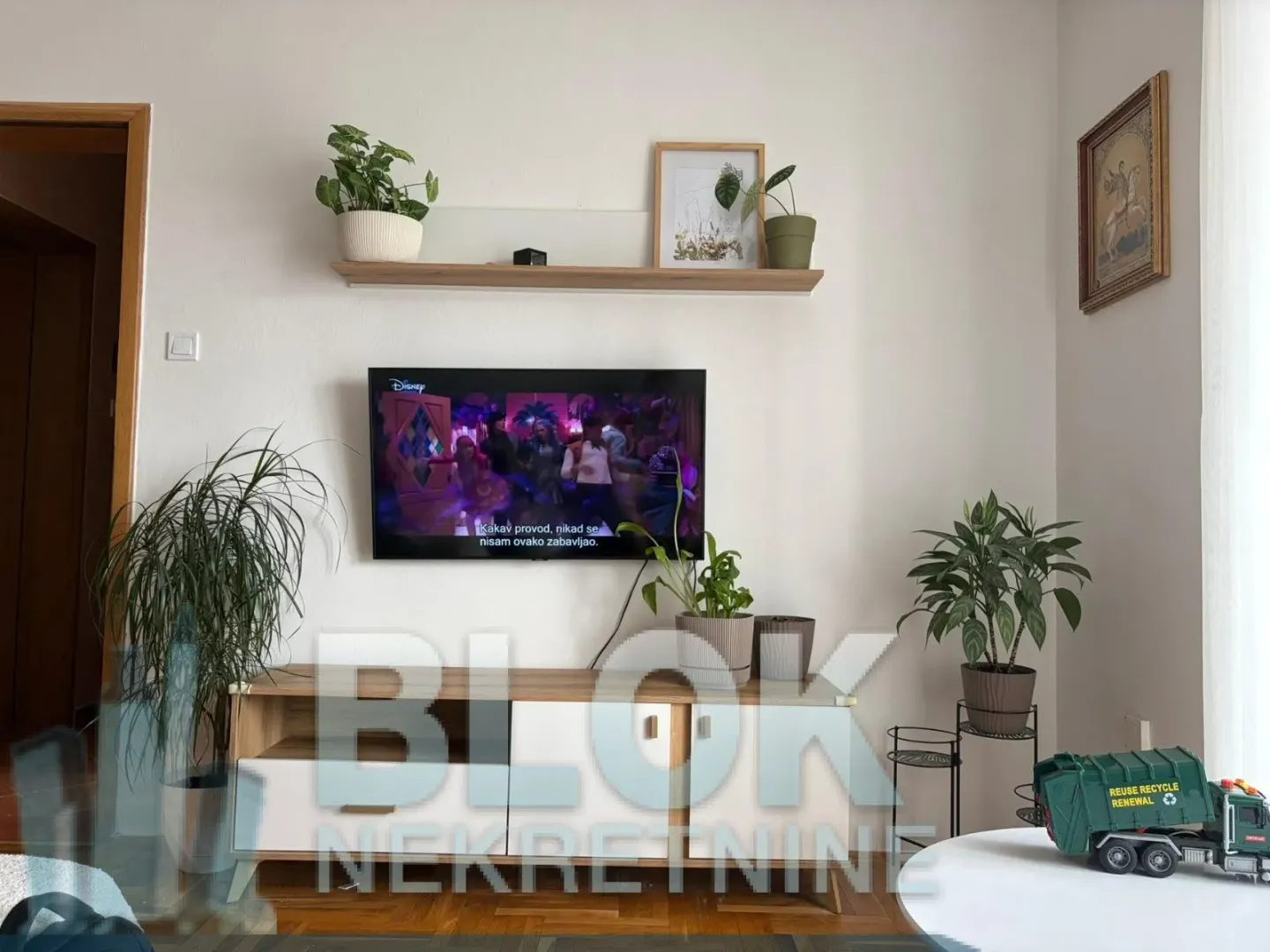 Living room with a wall-mounted TV and a wooden TV cabinet.