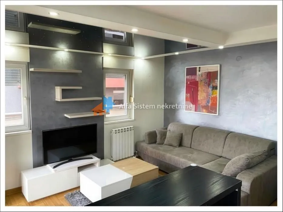 Living room with a sectional sofa, TV, and decorative wall shelves.