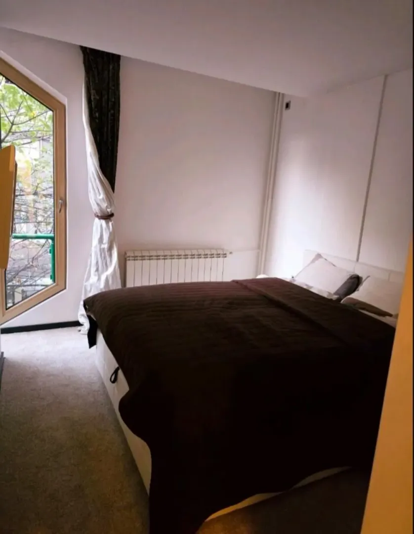 Bedroom with a double bed and an unusually shaped window.
