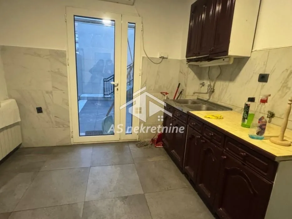 Small kitchen with dark wooden cabinets and an exit to the courtyard.