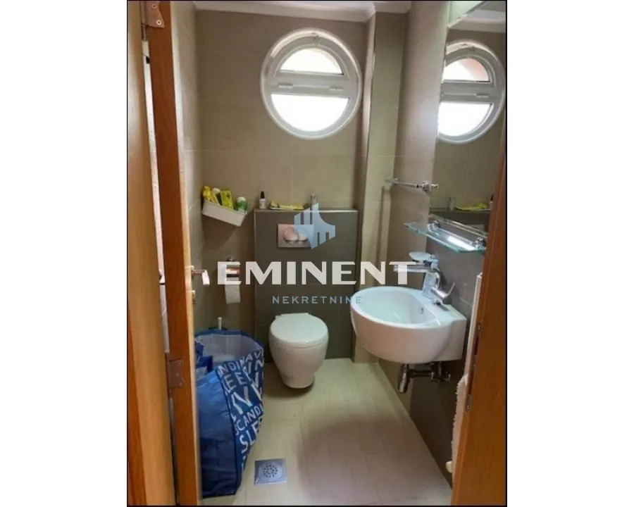 Smaller bathroom with a washbasin, toilet, and round window.