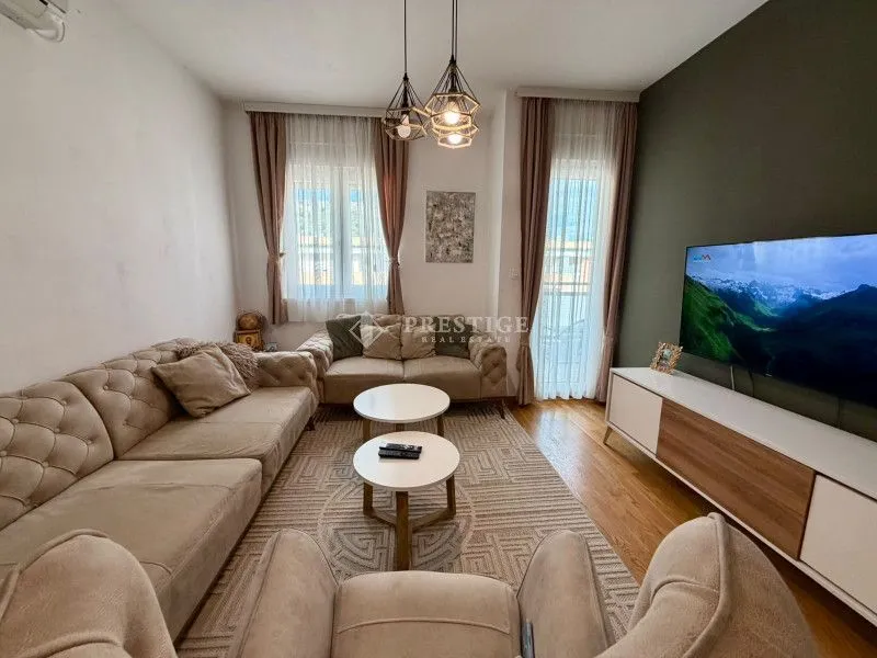 Dnevna soba sa garniturom, stočićima i televizorom.