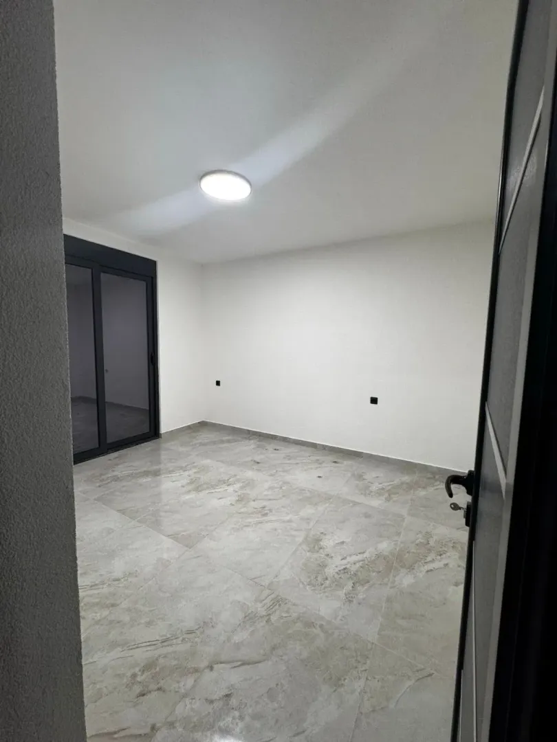 Empty room with ceramic floor tiles and balcony doors.