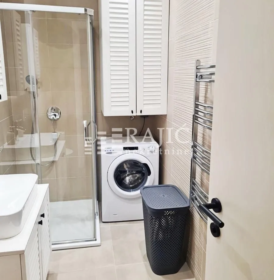 Modernly equipped bathroom with a shower cabin, washbasin, and washing machine.