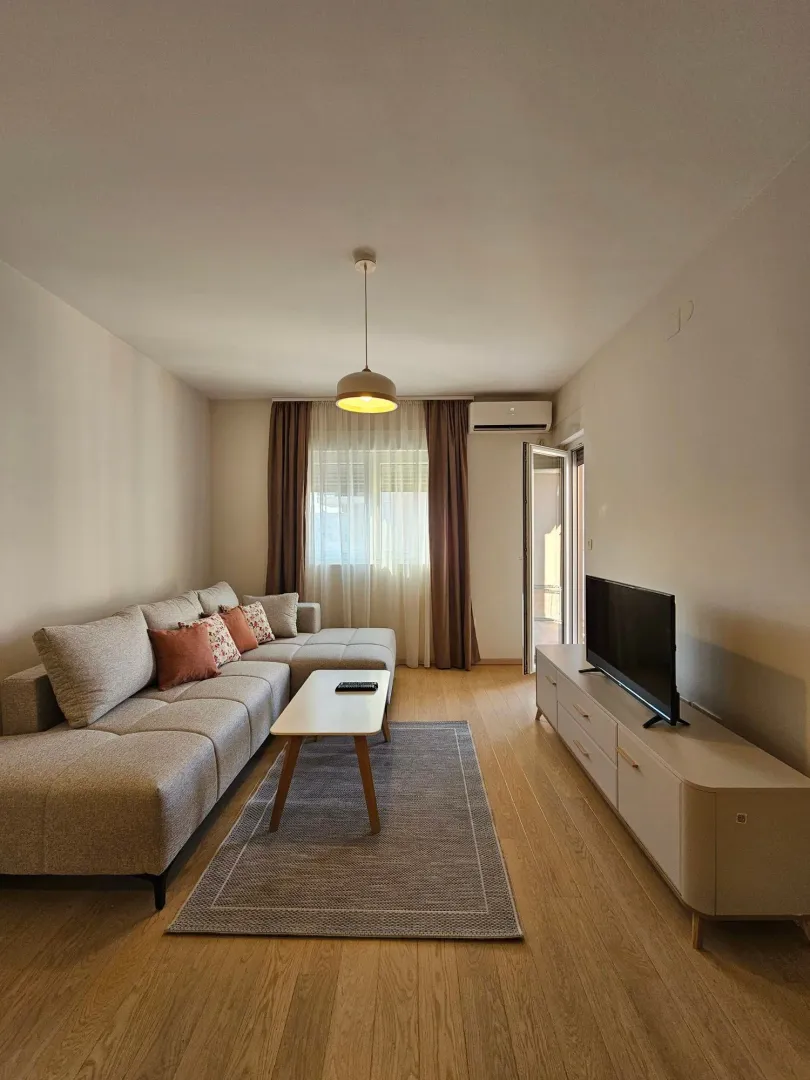 Furnished living room with a sectional sofa, TV unit, and access to the terrace.