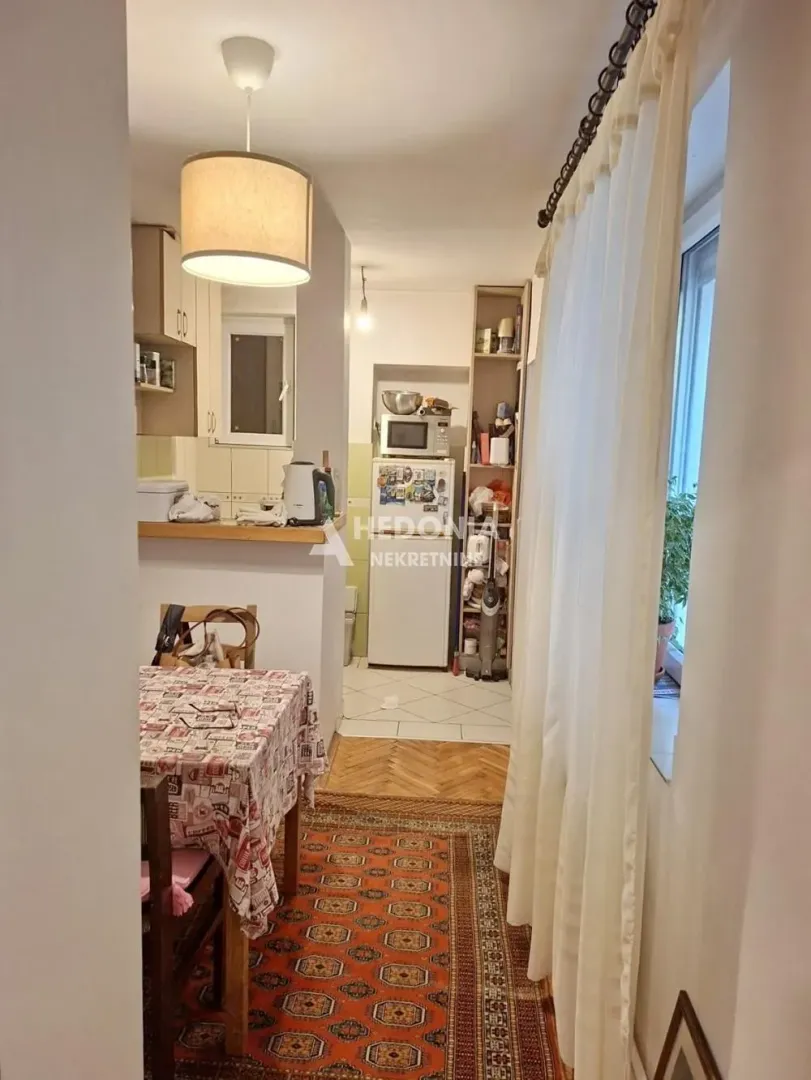 Kuhinja sa trpezarijskim stolom i pogledom na unutrašnjost stanovanja.