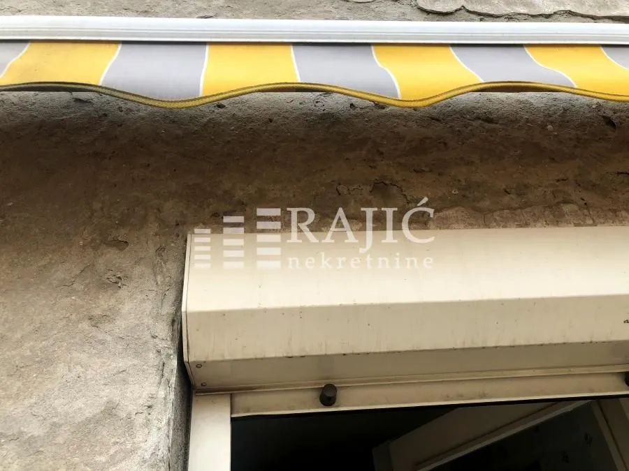 Building facade with an awning and window shutters.
