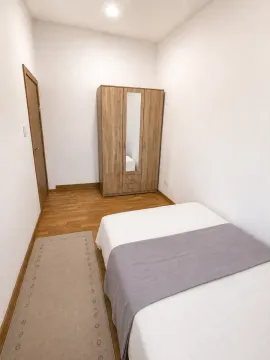 Jednostavna spavaća soba sa drvenim ormarom i krevetom. - image 4