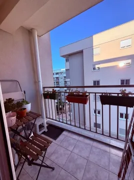 Small furnished balcony with a wooden table and flower planters. - image 5