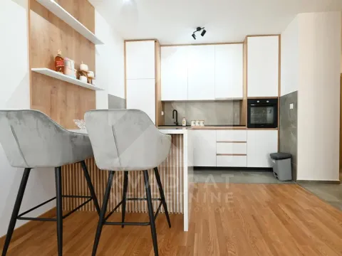 Modern kitchen with white units, a breakfast bar, and bar stools. - image 14