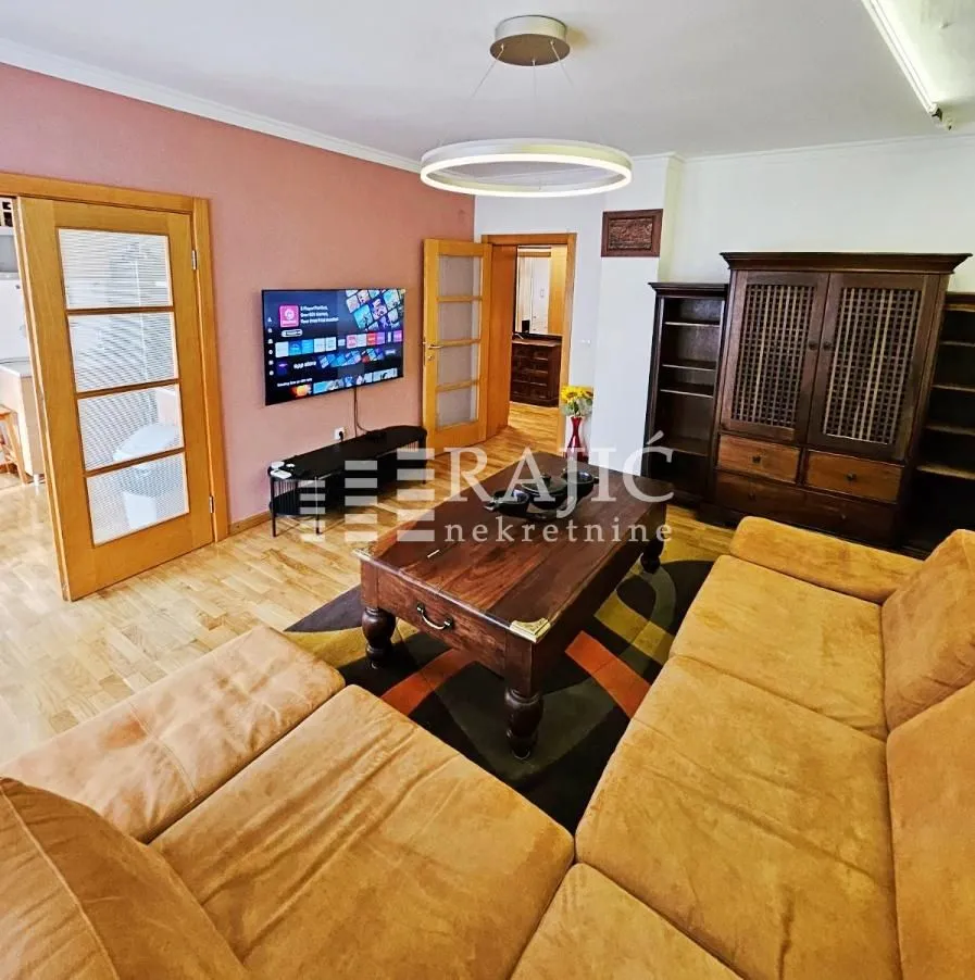 Living room with a sofa set, wooden furniture, and a TV.