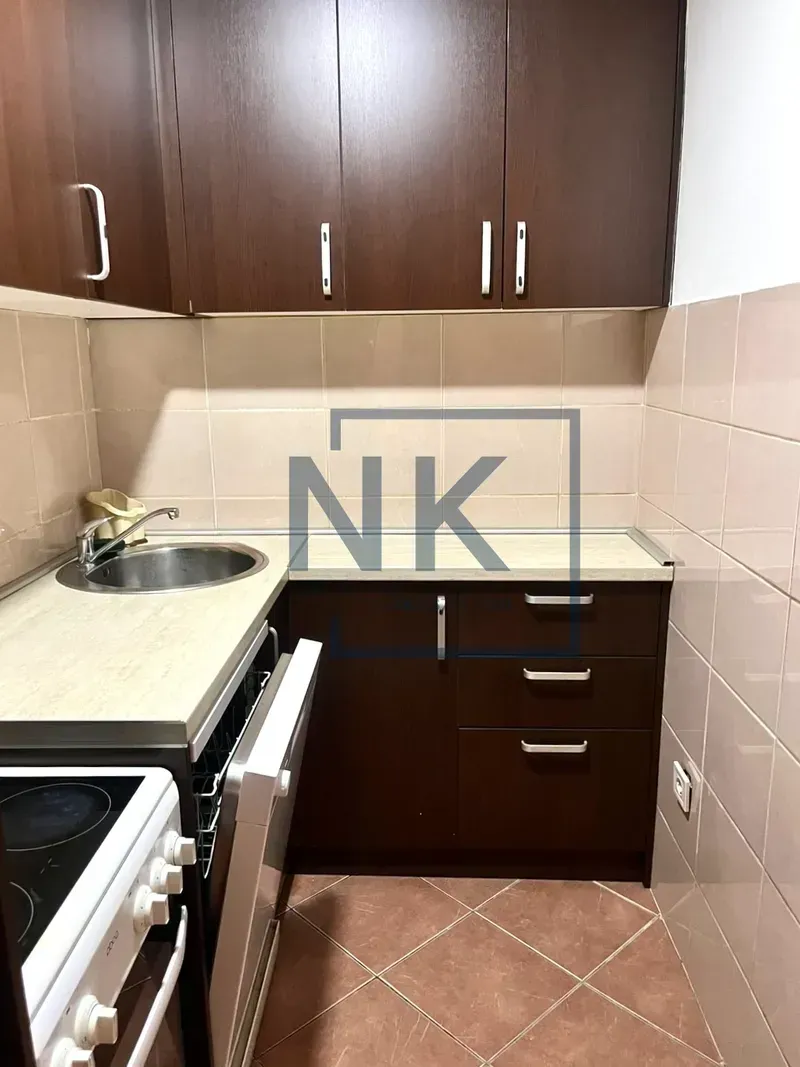 Small kitchen with dark wooden cabinets and ceramic tiles.