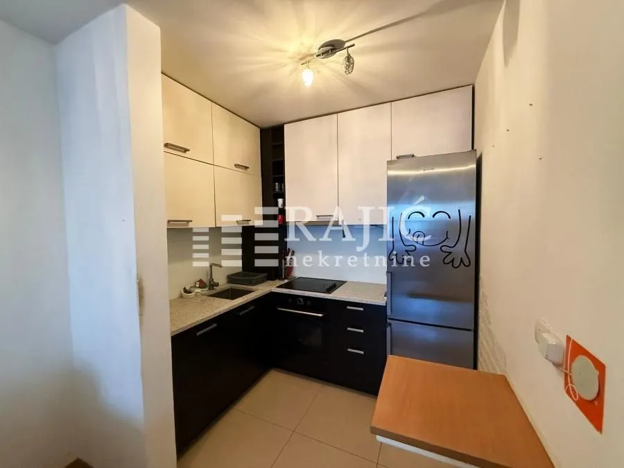 Small kitchen with white and dark cabinets and a refrigerator.
