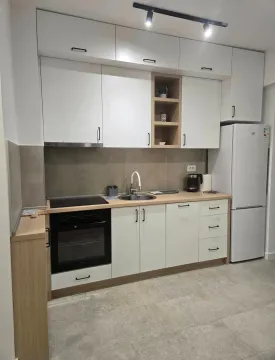 Moderna kuhinja sa bijelim elementima, ugradnom tehnikom i frižiderom. - image 2