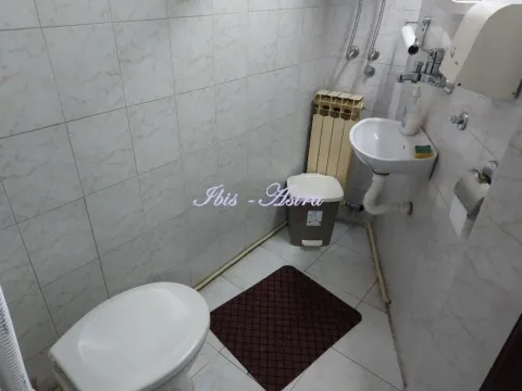 Smaller bathroom with a sink, toilet, and wall tiles. - image 8