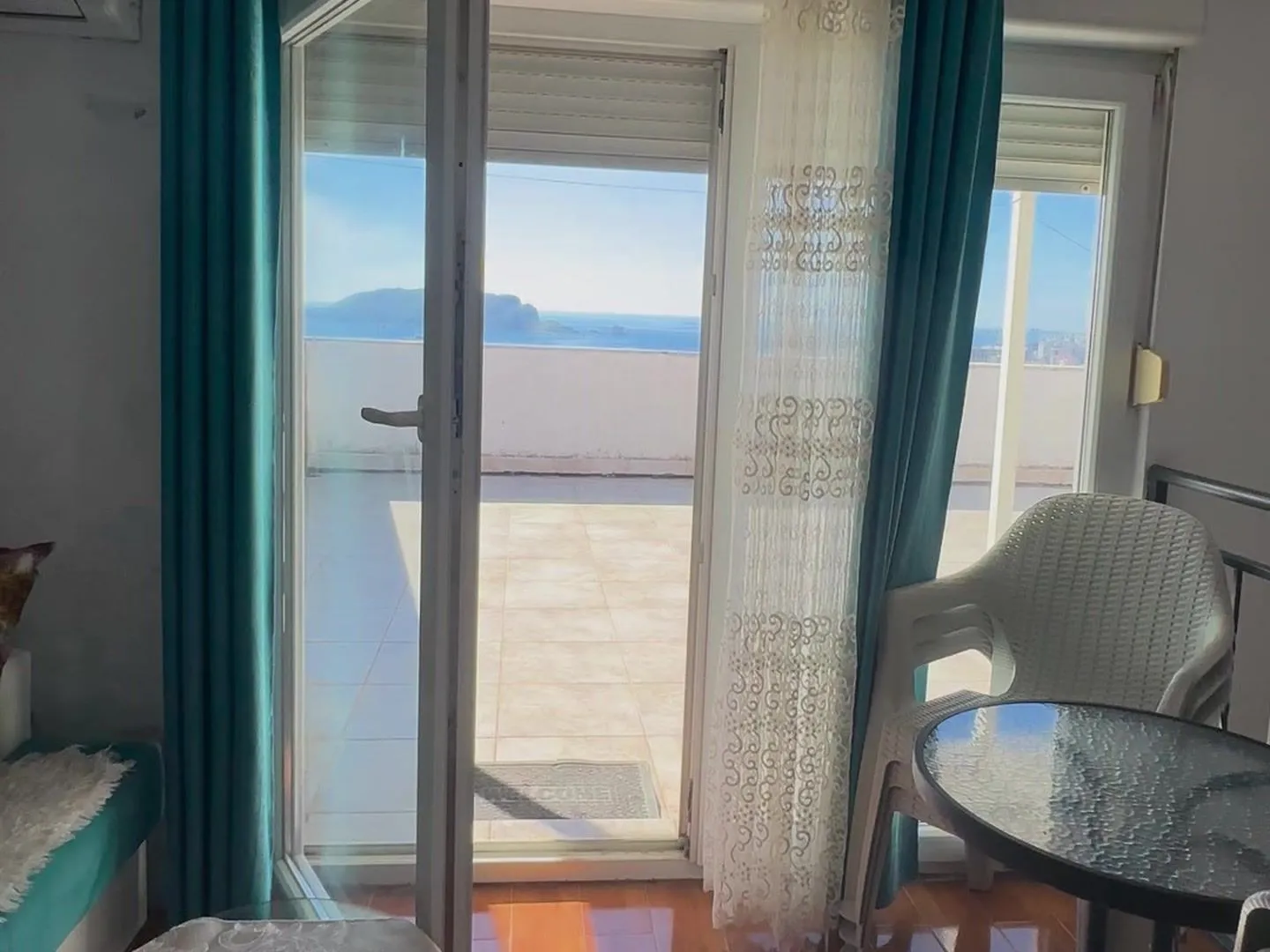 View through the balcony door to the terrace and sea.