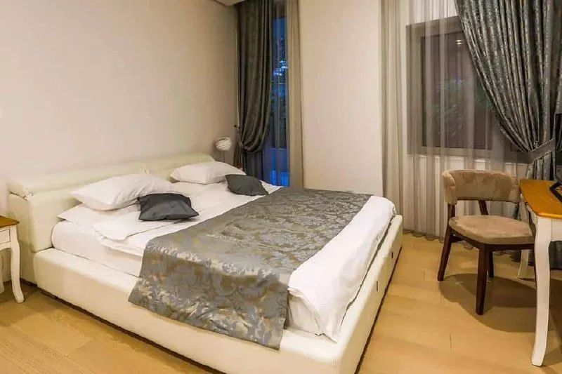 Prostrana spavaća soba sa bračnim krevetom, radnim stolom i velikim prozorom.