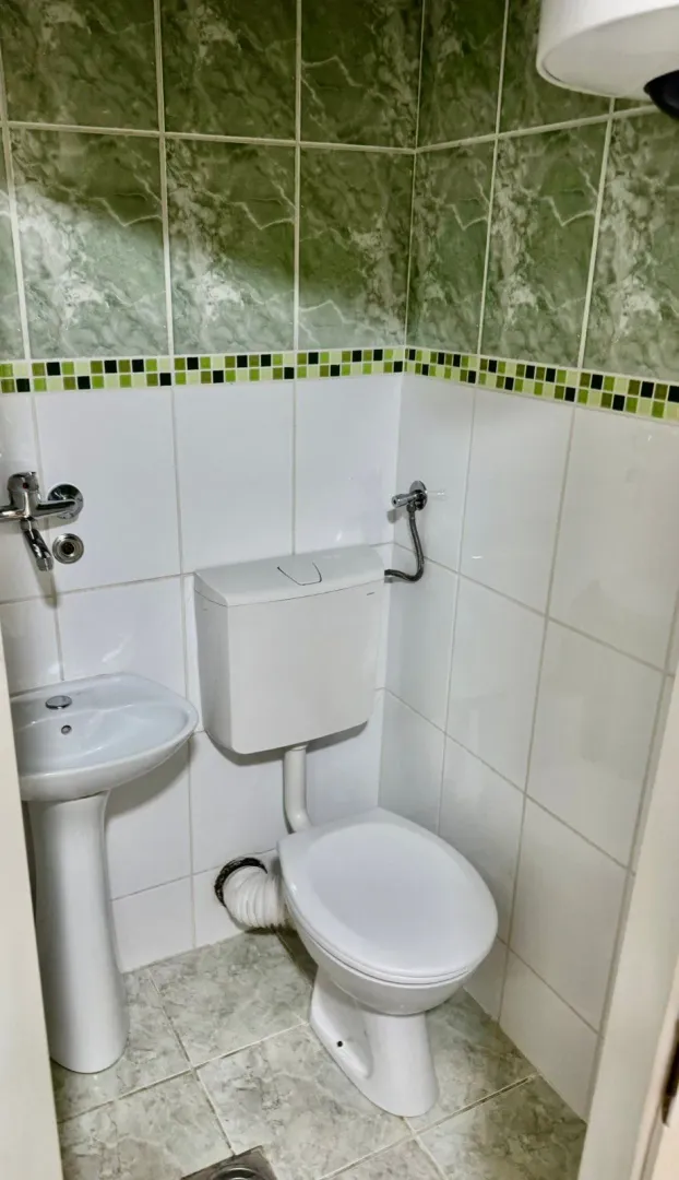 Manje kupatilo sa bijelim pločicama i sanitarijama.
