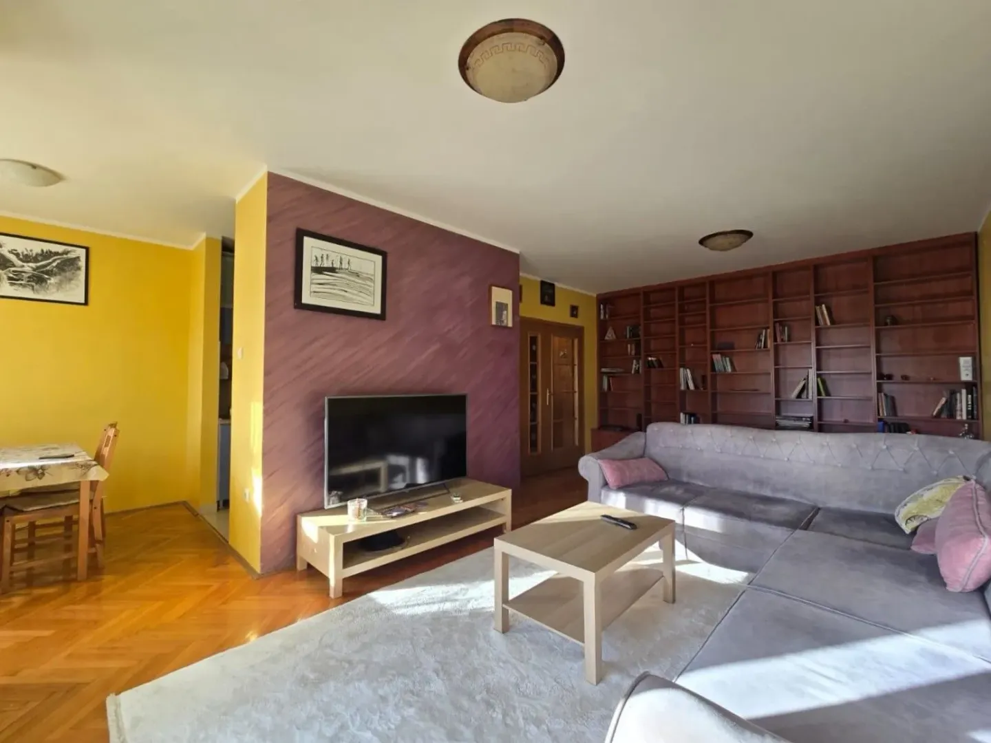 Spacious living room with a sofa, television, and built-in bookshelves.