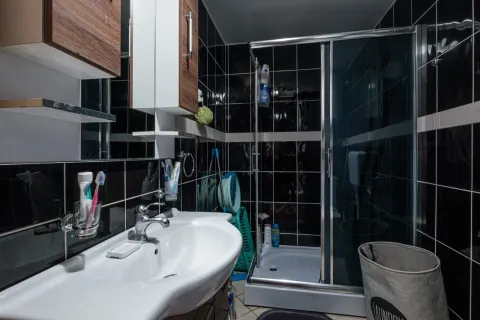 Kupatilo sa crnim pločicama, umivaonikom i tuš kabinom. - image 13