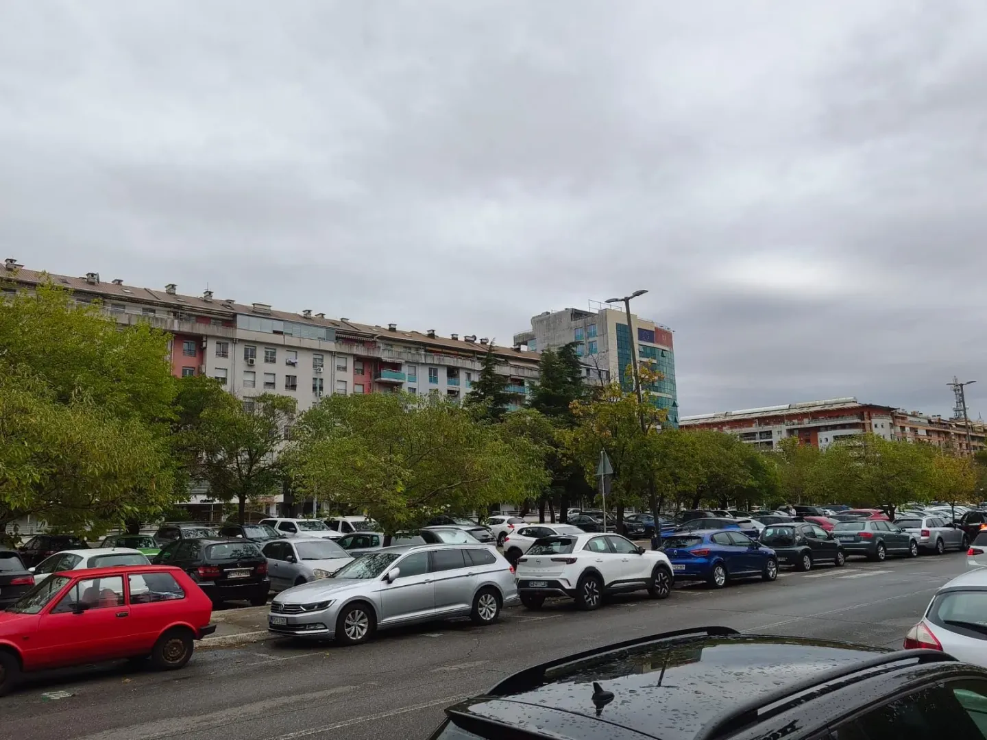 View of the parking lot in front of the building with parked cars.