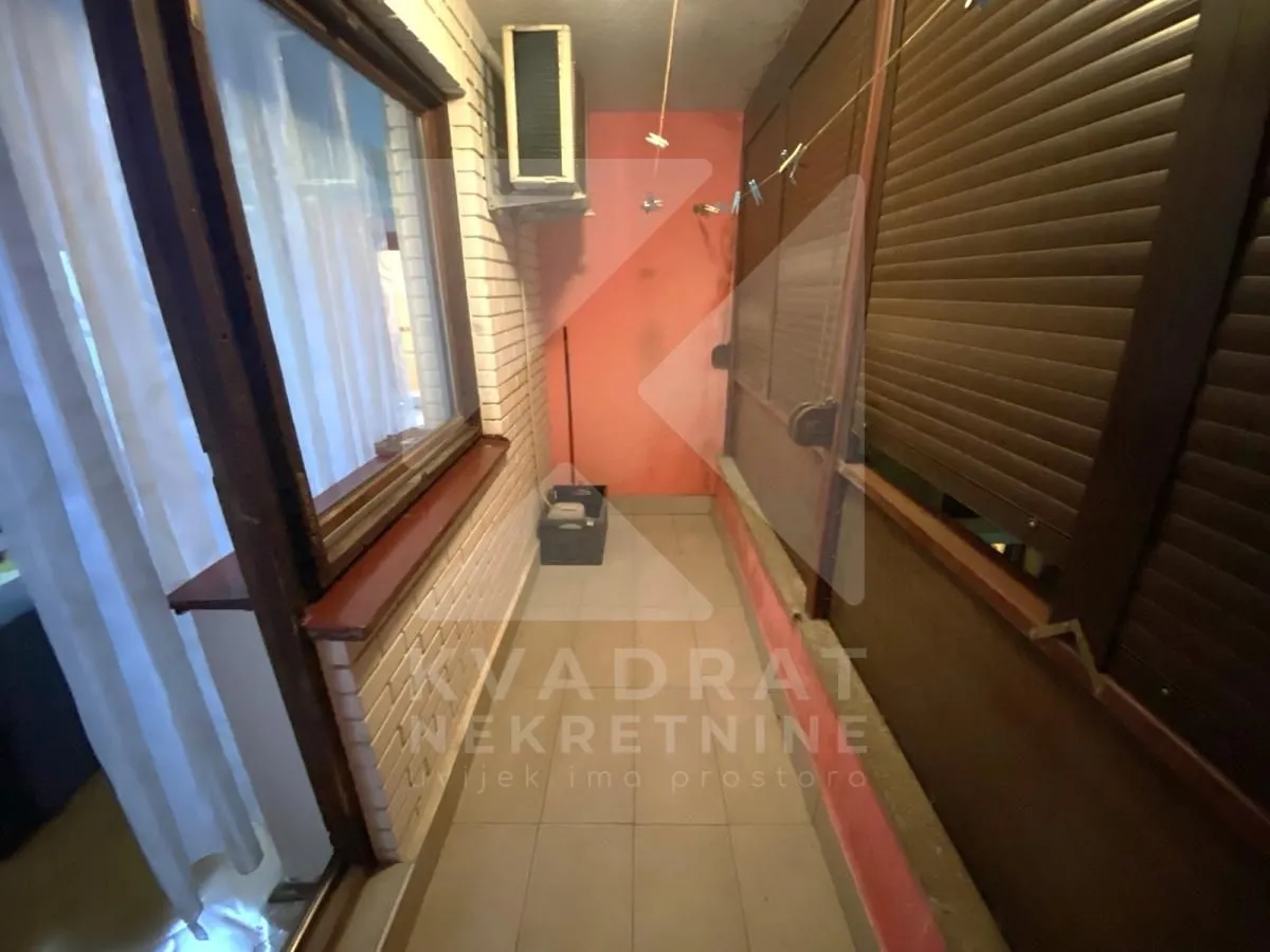 Zastakljeni balkon sa roletnama i prozorom.