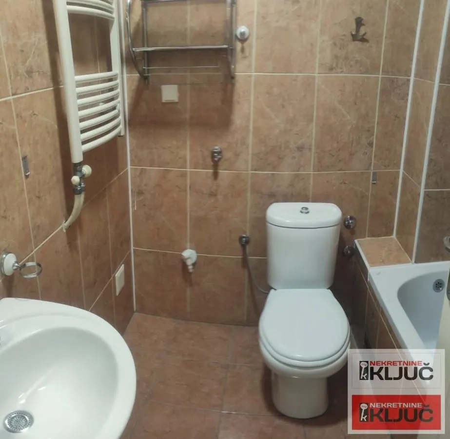 Kupatilo opremljeno sanitarijama i pločicama u braon tonovima.